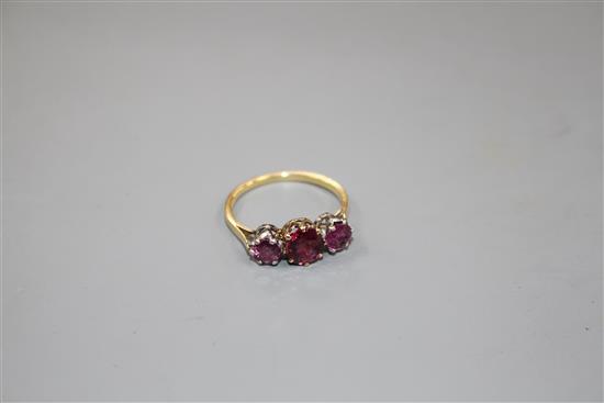 An 18ct and three stone ruby and garnet?? set dress ring, size M, gross 2.7 grams.